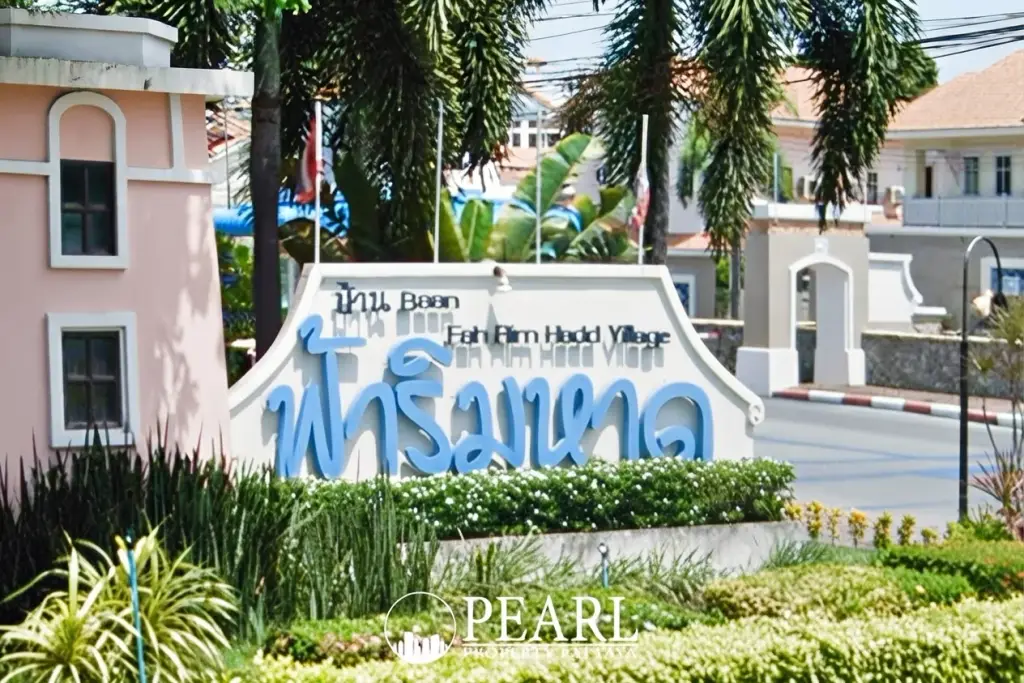 Fa Rim Haad Village entrance sign with blue Thai script, English text, and lush green landscaping.