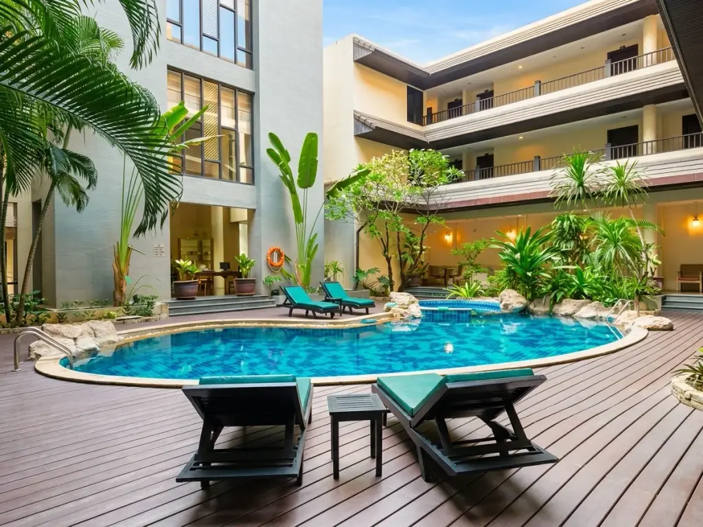 Nirvana Place courtyard pool with wooden deck, loungers, and tropical palm landscaping