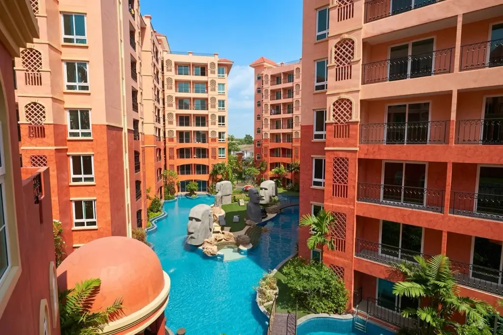 Seven Seas Condo Resort aerial view of pool courtyard with Moai statues surrounded by pink high-rise towers in Pattaya