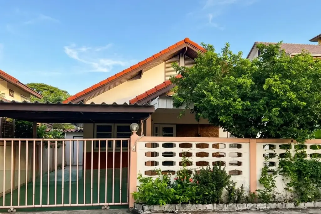 Sangchai Villa exterior with a red tiled roof, carport, and a patterned white fence with a green gate in Pattaya, Thailand.