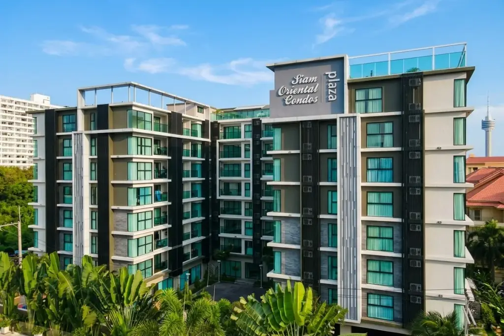 Siam Oriental Plaza exterior of modern condo building with lush tropical landscaping and palm trees under a clear sky.