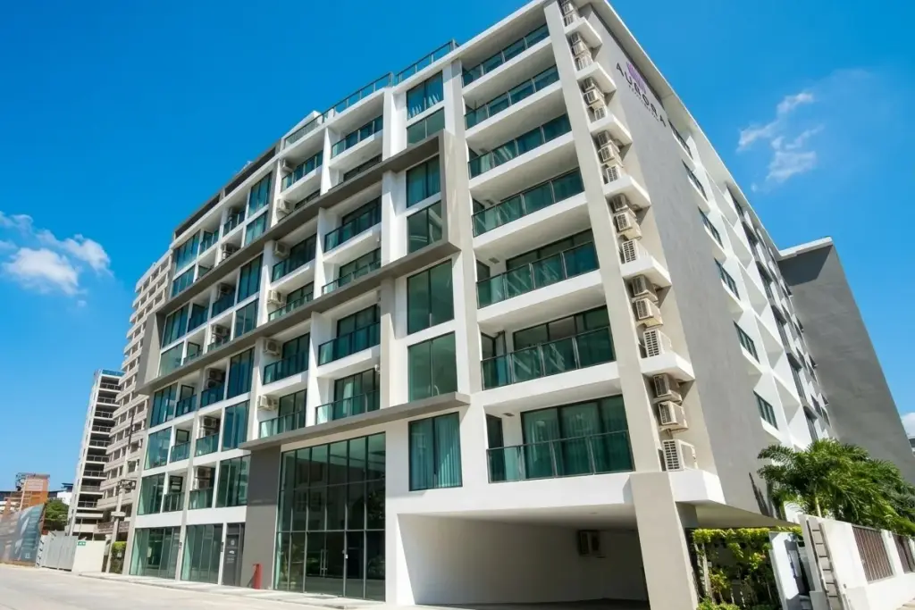 Aurora Pratumnak modern condo building exterior with multiple stories, balconies, large windows, and street view.