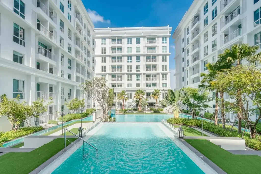 The Orient Resort & Spa exterior view of white condo buildings surrounding a long swimming pool and green courtyard.