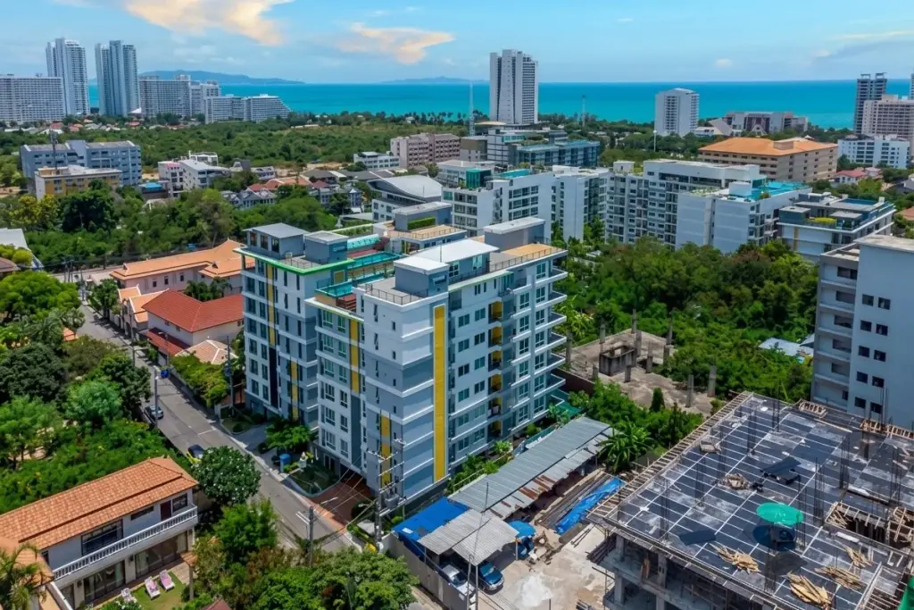 Estanan Condo: Modern building facade with green, white, and yellow panels, large windows, and balconies.