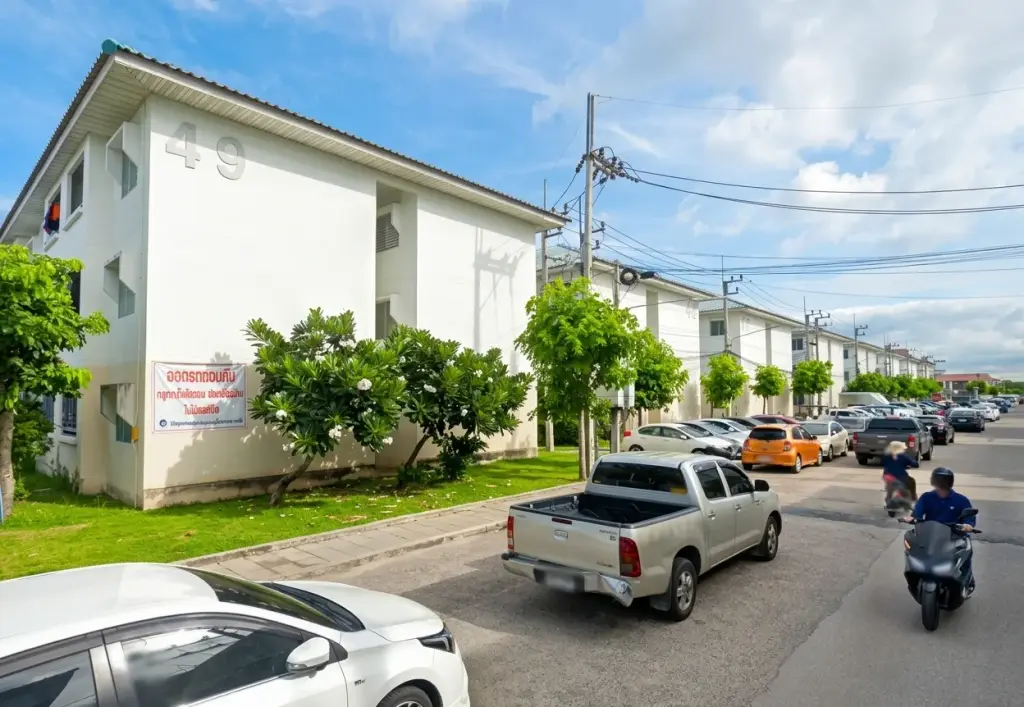 Eua Arthorn Naklua white low-rise condo building exterior with parked cars and tree-lined street
