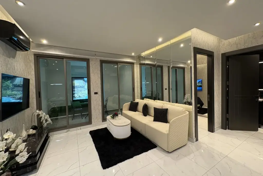 2 Bedroom Condo for Sale at Zenith Pattaya living room with cream sofa, mirrored wall, and glass balcony doors