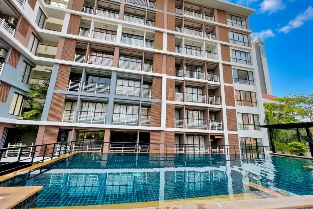 The Pride outdoor swimming pool with blue tiles reflecting the multi-story condo building with balconies and windows.
