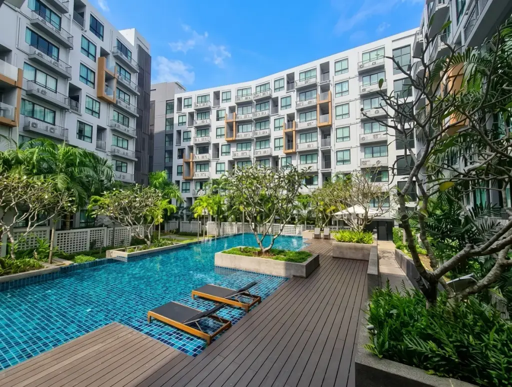 Stasia Dormy Residence outdoor swimming pool with wooden deck surrounded by condo towers and tropical landscaping