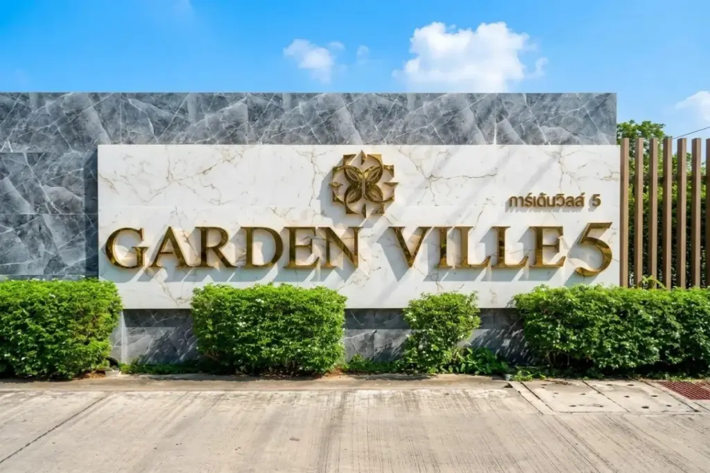 Garden Ville 5 entrance sign with gold lettering on marble wall and green hedges in Pattaya