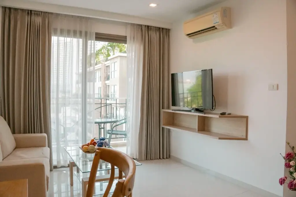 1 Bedroom Condo for Rent at City Garden Tropicana living room with mounted TV, sofa, and balcony access