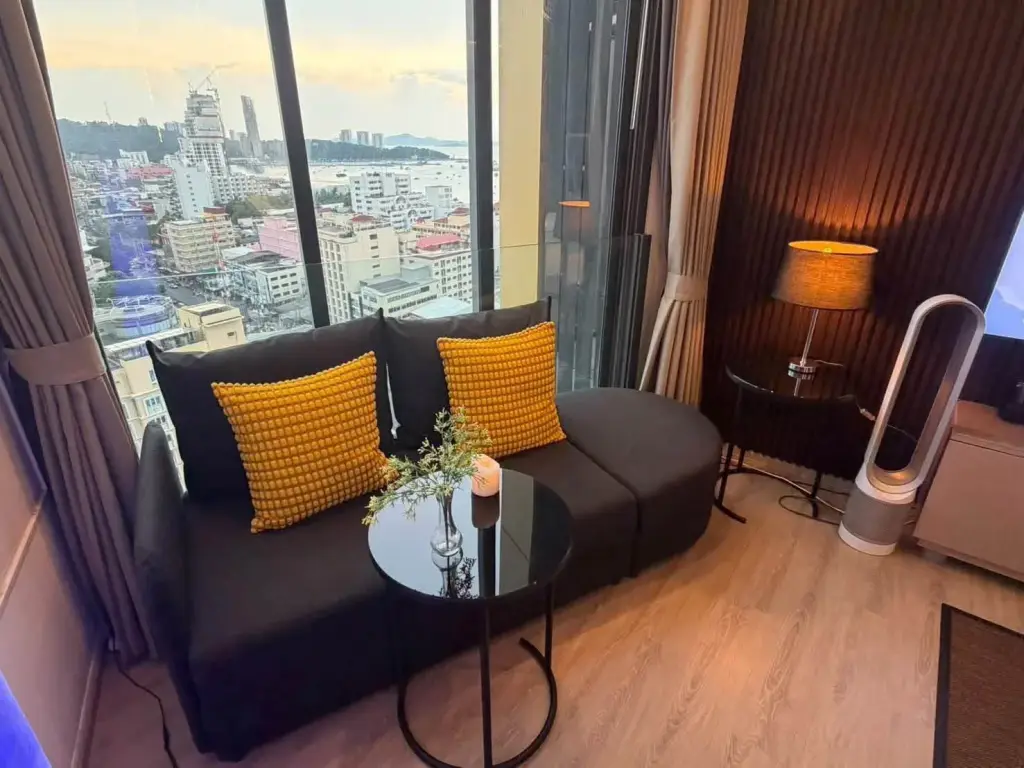 Studio Condo for Rent at EDGE Central Pattaya living area with sofa, yellow pillows, and city skyline view