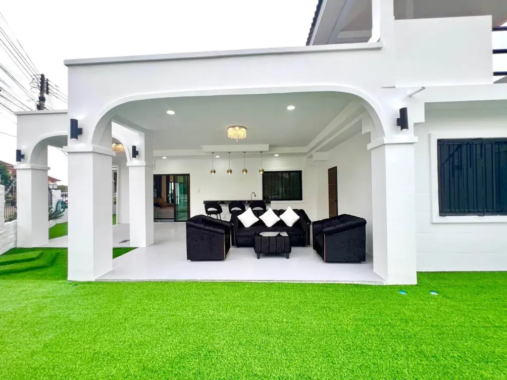 3 Bedroom House for Rent at Ekmongkol 1 Village covered patio with black sofas and artificial turf lawn