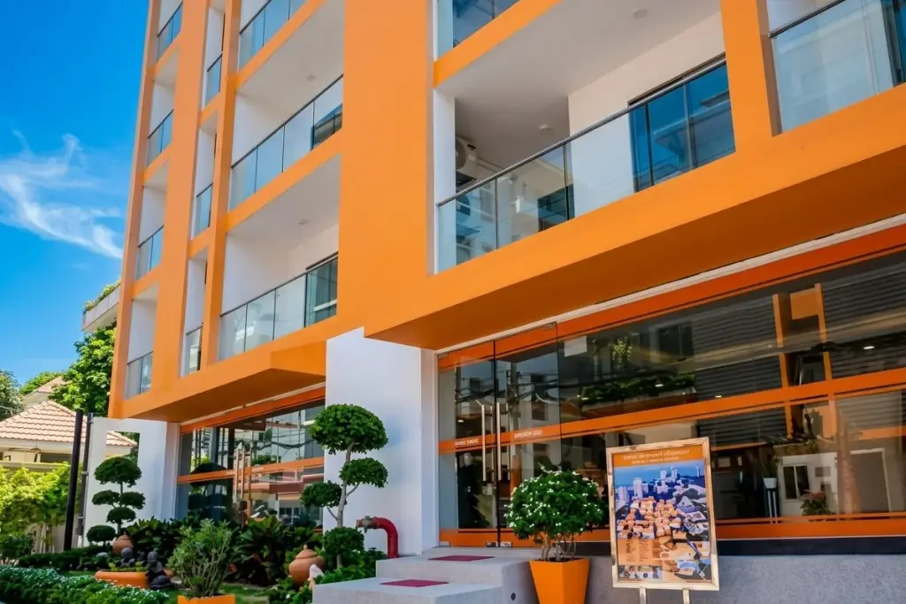 C View Residence Pattaya exterior, an orange and white building with glass entrance, steps, and landscaped garden.