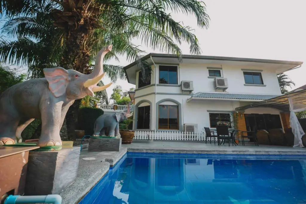 7 Bedroom House for Rent in Jomtien two-story house exterior with pool, elephant statues, and palm trees