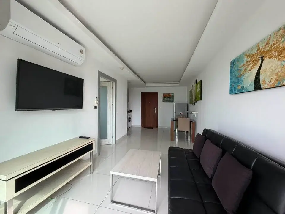 1 Bedroom Condo for Sale at Laguna Beach Resort 1 living room with black leather sofa, mounted TV, and dining area