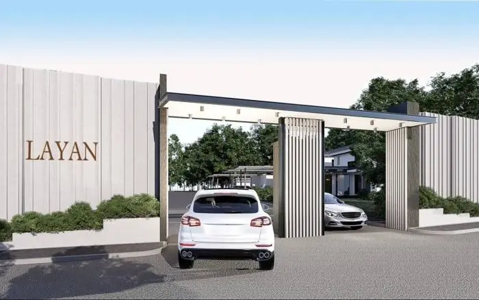 Layan Residence Pattaya modern entrance gate with "LAYAN" sign, white SUV, and green landscaping.