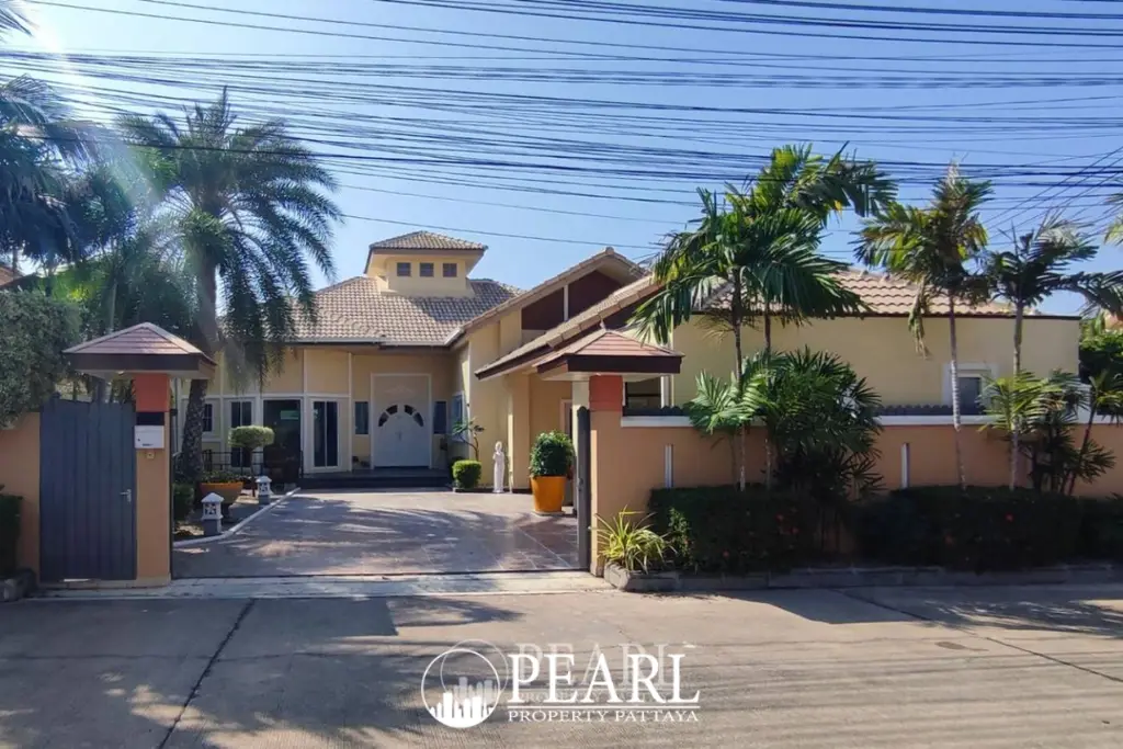 Classic Villa exterior front view with driveway, ornate gate, and palm trees under a clear sky.