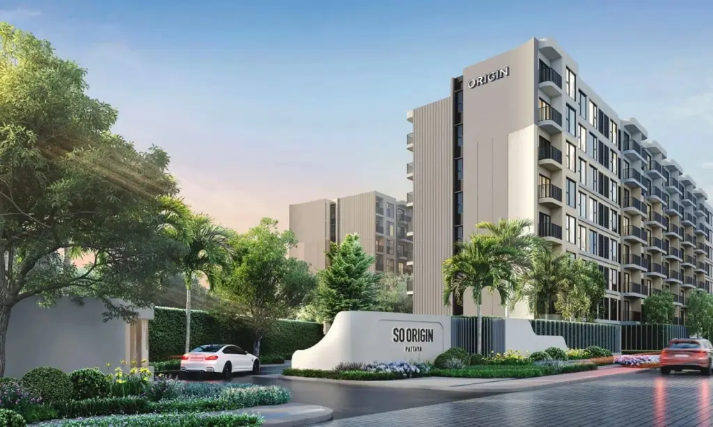 The Origin Pattaya, modern condo buildings with red, grey, and white facades, a central driveway, and landscaping.
