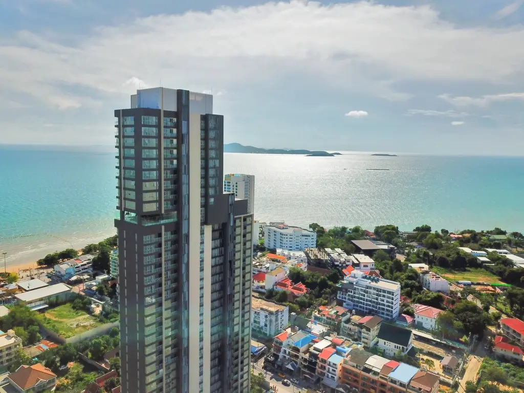 The Panora Pattaya high-rise condo building at sunset, overlooking the ocean and coastline.