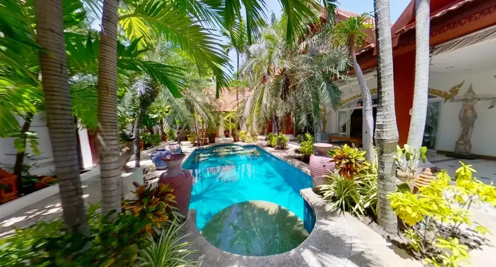Jomtien Palace Village small, curved plunge pool with blue tiles, surrounded by lush tropical plants and a rustic brick wall