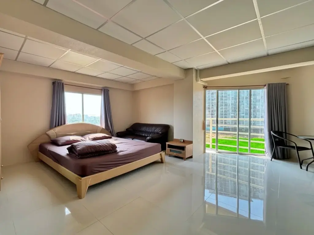 2 Bedroom Condo for Sale at Jomtien Beach Condominium bedroom with wooden bed, leather sofa, and balcony city view
