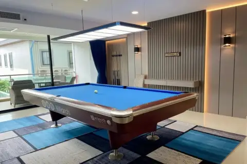1 Bedroom Condo for Sale at Gardenia Pattaya close-up of blue felt billiard table with cue rack and slatted accent wall with warm lighting