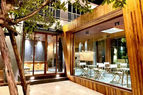 10 Bedroom House for Sale in Na Chom Thian: Exterior of the 'Greyduck Lobby' entrance and adjacent cafe area at night.