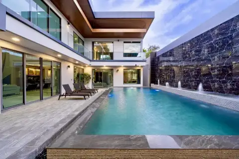6 Bedroom House for Sale at M Mountain Village private pool with fountain wall, glass balustrade balcony, and stone tile surround at dusk
