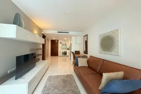 2 Bedroom Condo for Sale & Rent at The Sanctuary Wongamat spacious living room with TV unit, leather sofa and open kitchen