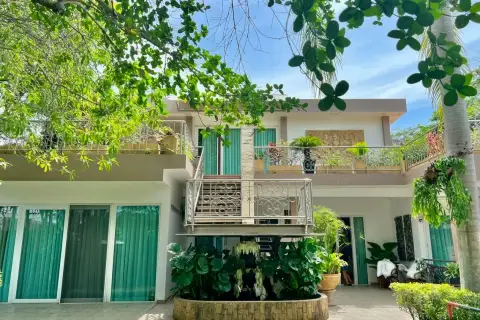 4 Bedroom House for Sale at Mountain Village 1 exterior view of two-story home with balconies and lush garden trees