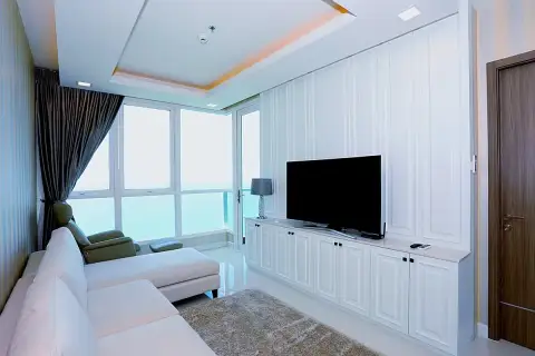 1 Bedroom Condo for Sale at Del Mare bright living room with white L-shaped sofa, flat-screen TV, and floor-to-ceiling sea-view windows