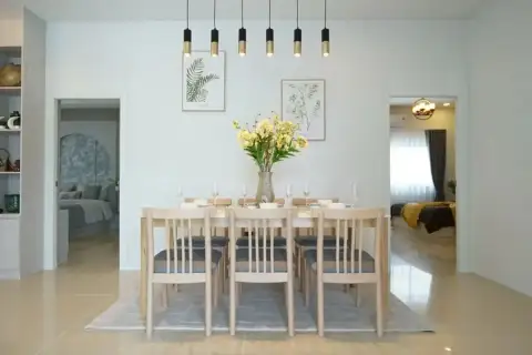 Phonthep Garden Ville 2 dining room with large wooden table, pendant lights, botanical wall art, and views to bedrooms