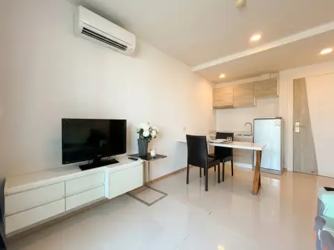 1 Bedroom Condo for Sale at Acqua Condo open-plan kitchen with dining table and wall-mounted TV