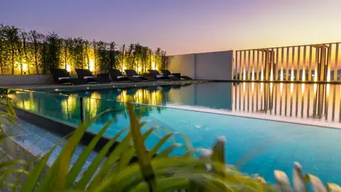 MaxxCity Condo rooftop infinity pool with lounge chairs overlooking city skyline at sunset