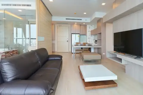 1 Bedroom Condo for Sale at Cetus Beachfront open-plan living area with leather sofa, kitchen, dining table, and glass-enclosed bathroom