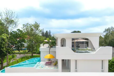6 Bedroom House for Sale in Huai Yai side view of pool terrace with yellow umbrella sun loungers and upper balcony seating