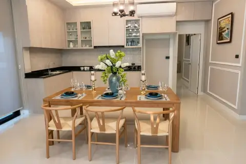 SP Village 1 kitchen and dining area with wood cabinets, black countertops, and 6-seat wooden dining table with wishbone chairs