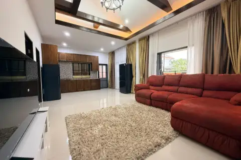 3 Bedroom House for Sale at Baan Dusit Pattaya Park living room with red sofa, rug, and kitchen in background.