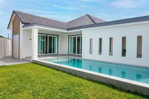 Boonraksa​ Haven​ private lap pool with green lawn, sliding glass doors, and covered patio at rear of house