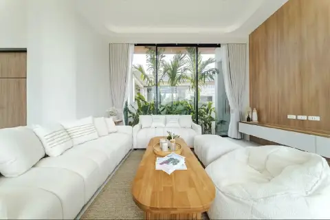 4 Bedroom House for Sale in Na Jomtien living room with white sofas, wooden accent wall and garden view
