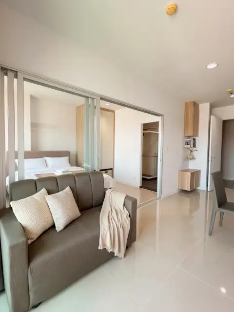 1 Bedroom Condo for Sale at Centric Sea living room with sliding glass partition to bedroom and gray sofa