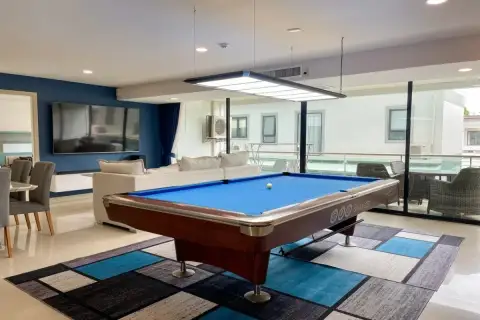 1 Bedroom Condo for Sale at Gardenia Pattaya billiards room with blue pool table, pendant light, white sofa and glass balcony doors