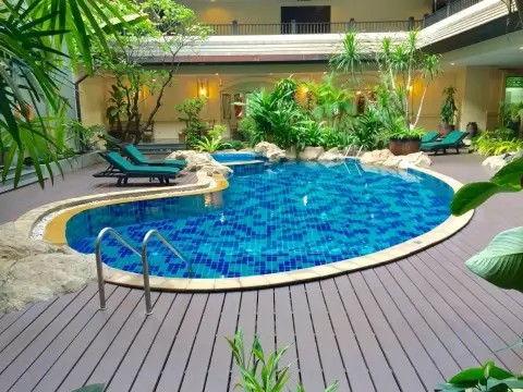 Nirvana Place curved tropical pool with teal loungers and lush garden landscaping