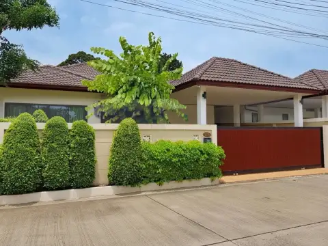 Garden Ville 1 modern house exterior with white wall, dark brown gate, and covered parking area.