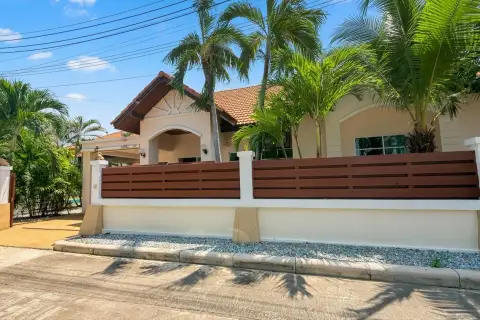 Mike Orchid Villas 2 house exterior with a modern fence, palm trees, and a tiled roof under a sunny sky.