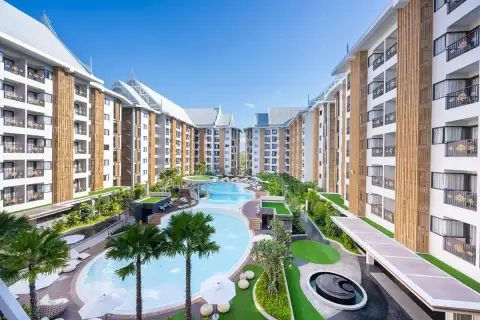 Wyndham Jomtien Pattaya aerial view of the outdoor swimming pool area with multiple pools, palm trees, and buildings.