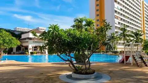View Talay 1 poolside garden with frangipani tree, water slide, and orange-accented tower