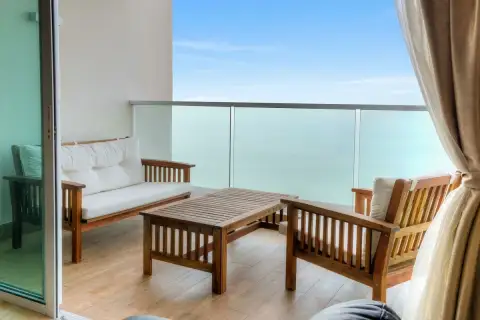 1 Bedroom Condo for Sale at Cetus Beachfront balcony with wooden sofa set, glass railing, and turquoise sea view