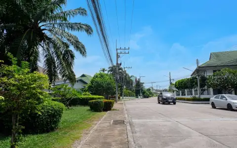 Baan Suan Suwattana Phase 2 entrance gate with security booth and barrier, leading to a residential street.