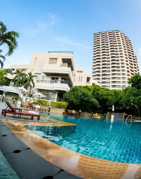 Rama Harbour View swimming pool area with lounge chairs and neighboring high-rise tower